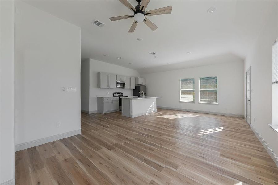 Unfurnished living room with ceiling fan, light wood-type flooring, and sink