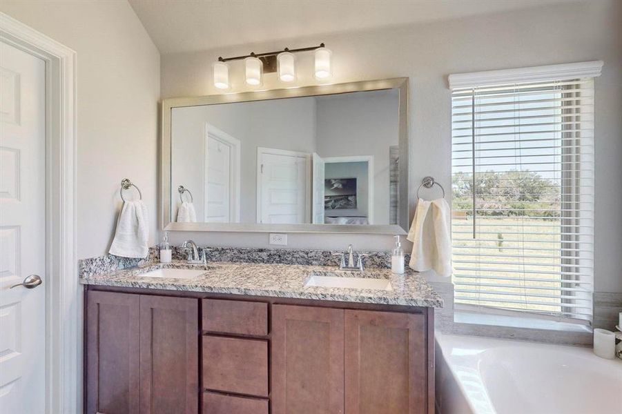 Bathroom featuring dual vanity, plenty of natural light, and a tub to relax in