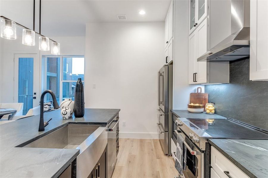 Kitchen featuring appliances with stainless steel finishes, wall chimney exhaust hood, and white cabinets