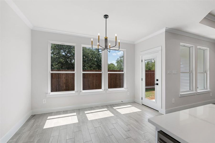 Unfurnished dining area with an inviting chandelier, crown molding, and light hardwood / wood-style flooring