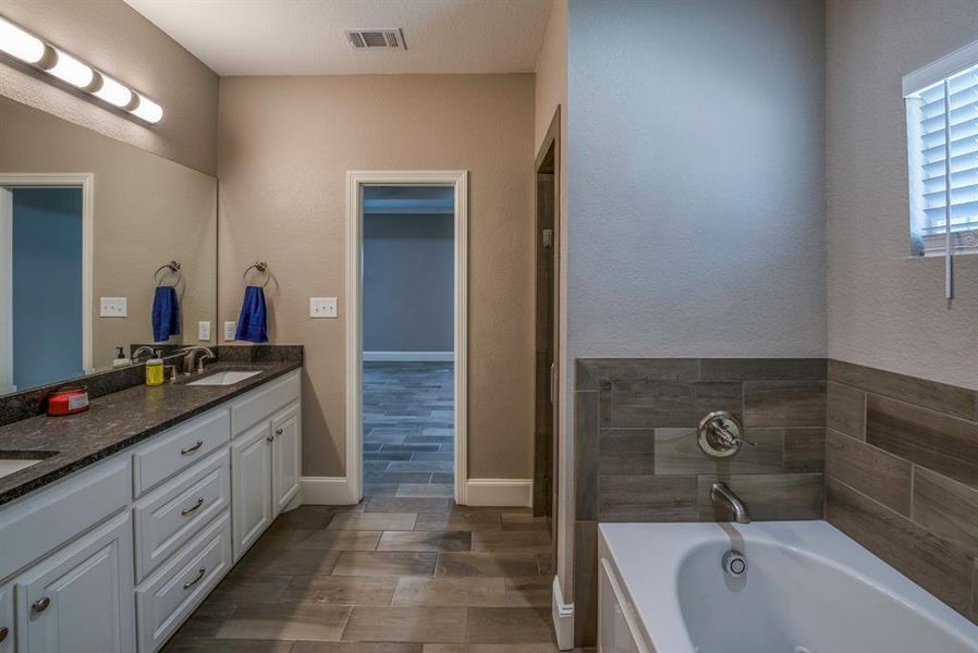 Bathroom with a bath, hardwood / wood tile flooring, and vanity