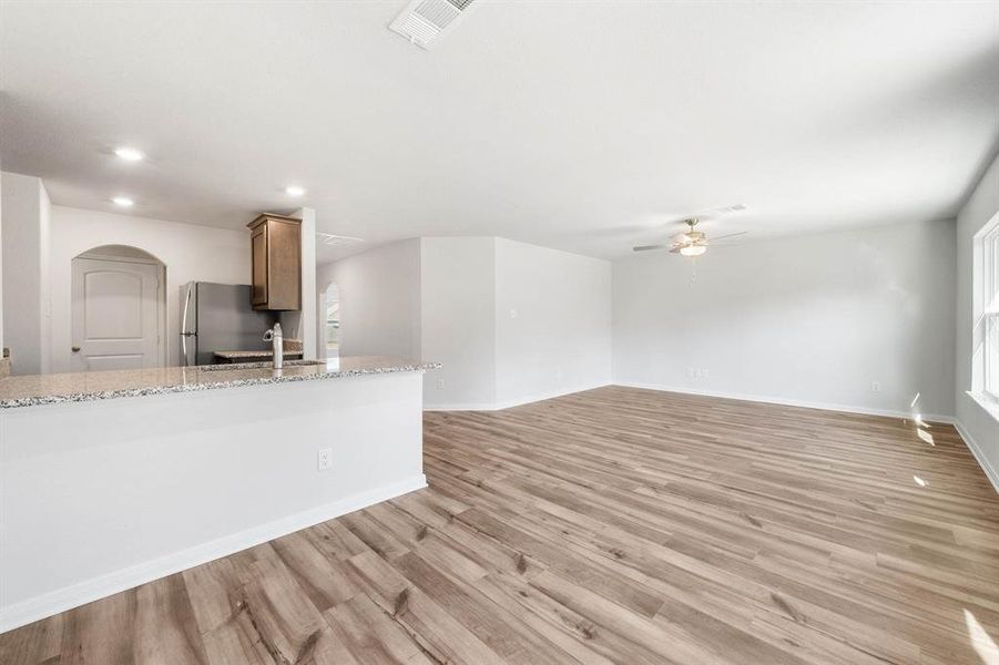 Unfurnished living room with ceiling fan, light hardwood / wood-style floors, and sink