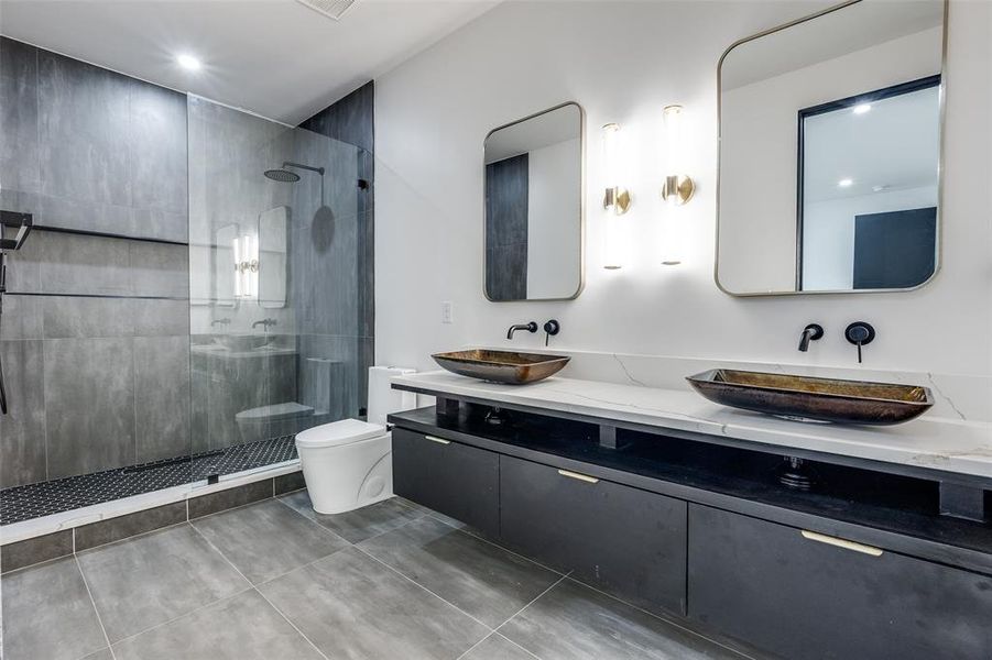 Bathroom featuring dual vanity, tile flooring, a shower with shower door, and toilet