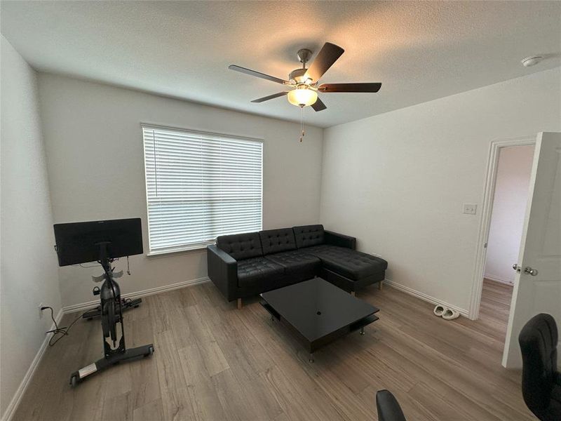 Living room featuring a textured ceiling, ceiling fan, and light hardwood / wood-style floors