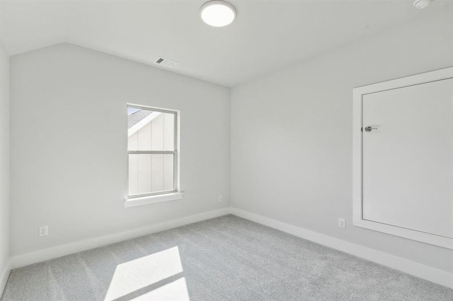 Spare room featuring lofted ceiling and light carpet