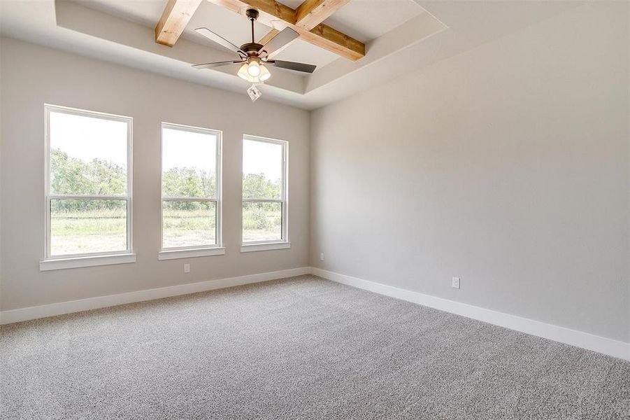 Spare room featuring coffered ceiling, ceiling fan, beamed ceiling, and carpet flooring