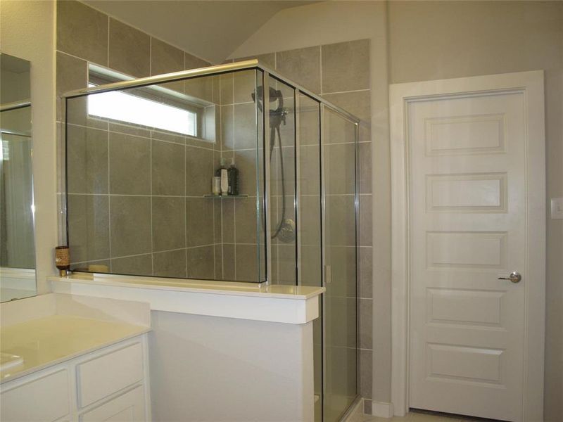 Bathroom featuring vaulted ceiling, a shower with shower door, and vanity