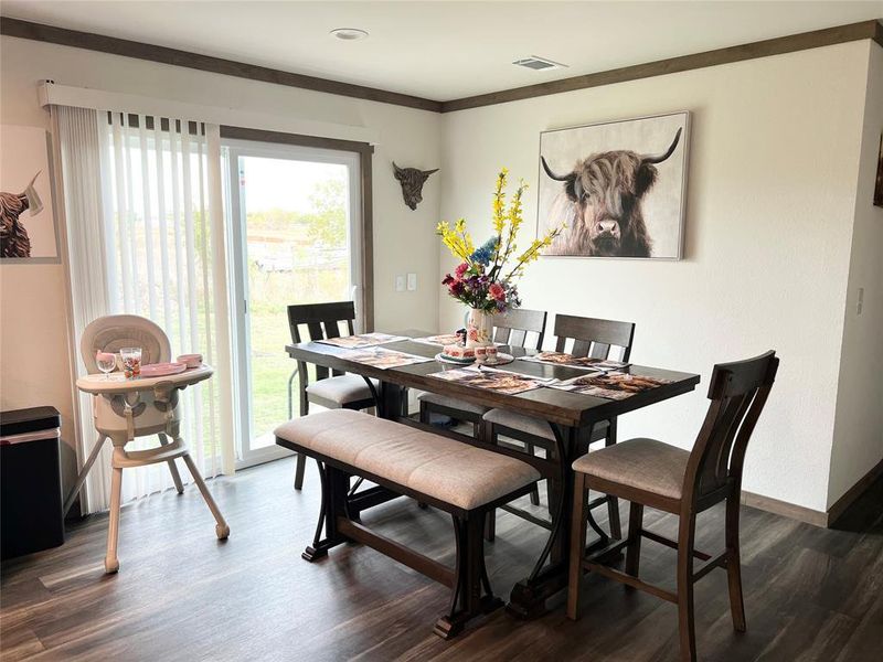 Dining room with dark wood-type flooring, crown molding, and a wealth of natural light