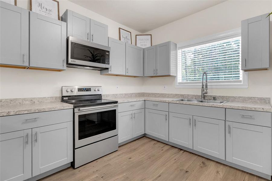 Modern kitchen with stainless steel appliances and a window providing natural light.