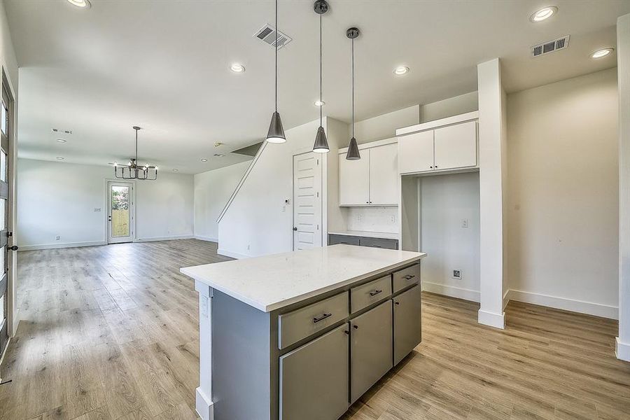 Kitchen featuring decorative light fixtures, light hardwood / wood-style floors, a center island, a chandelier, and white cabinetry