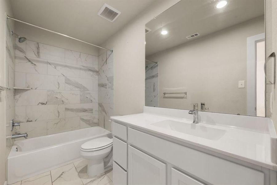 Secondary bathroom features light countertops and cabinets, neutral paint, shower/tub combo with tile surround, large mirror, tile floors, sleek fixtures and modern finishes, plenty of space to accommodate any visiting family or guests.