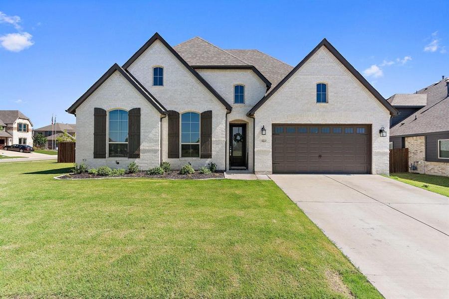 French country style house featuring a garage and a front yard