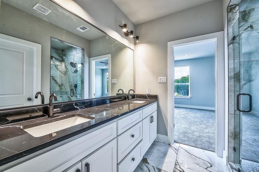 Bathroom with tile flooring, vanity with extensive cabinet space, an enclosed shower, and double sink