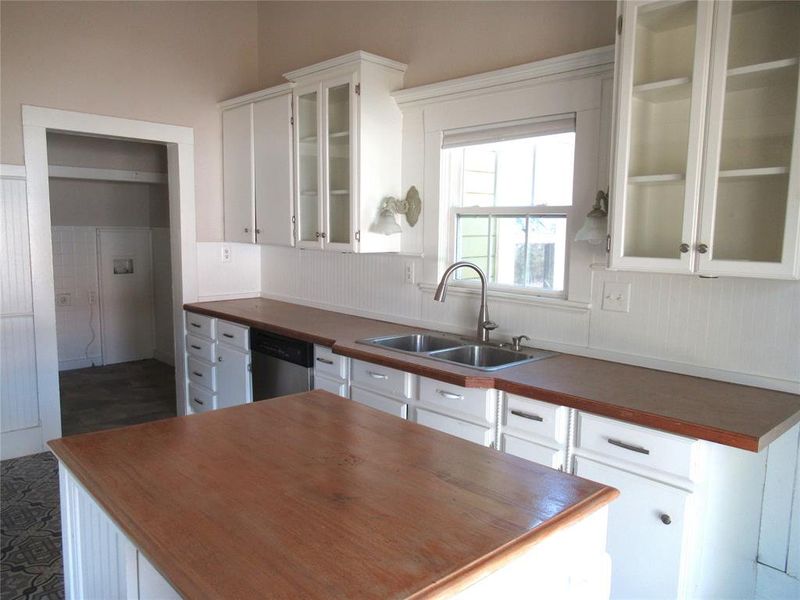 Kitchen featuring dishwasher, white cabinets, sink, and wooden counters