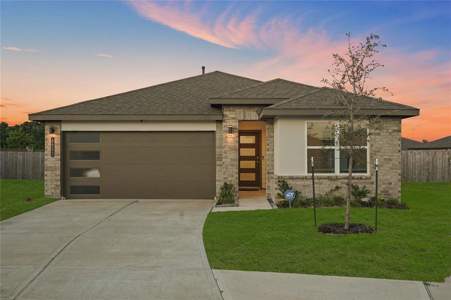 Welcome home to this single-story home with a modern design, featuring a two-car garage, a brick facade, and a modern front door with sidelights