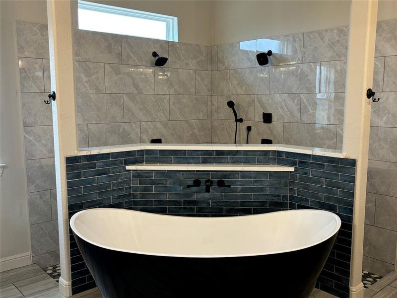 Bathroom with tile walls, tile floors, and shower with separate bathtub