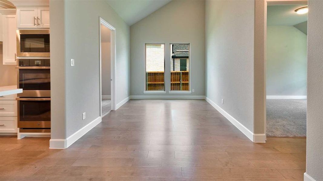 Corridor featuring lofted ceiling and light colored carpet