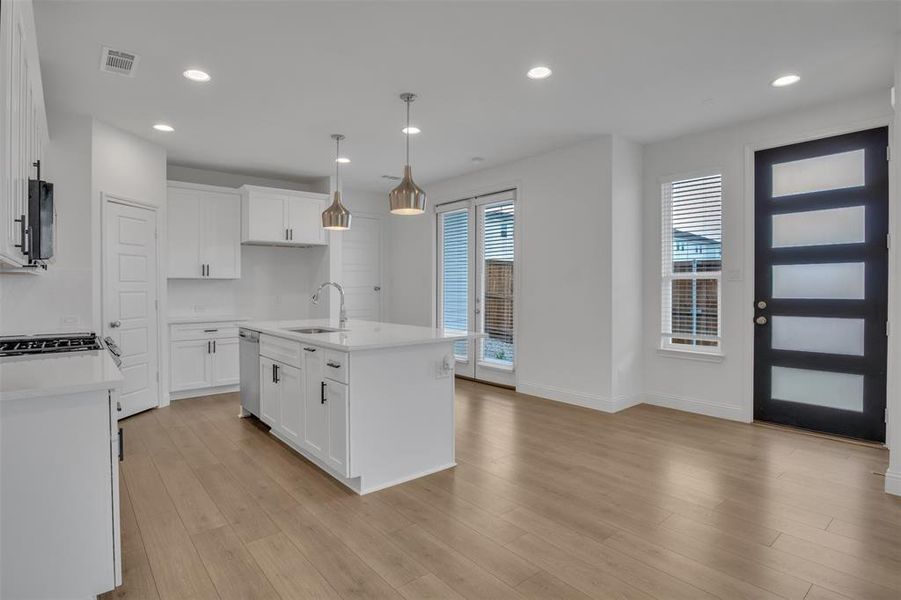 Kitchen with a wealth of natural light, a center island with sink, sink, and light wood-type flooring