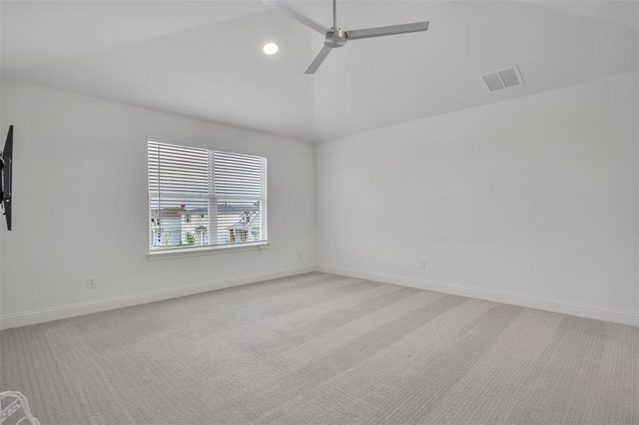 Primary bedroom with high vaulted ceiling, ceiling fan, and light carpet