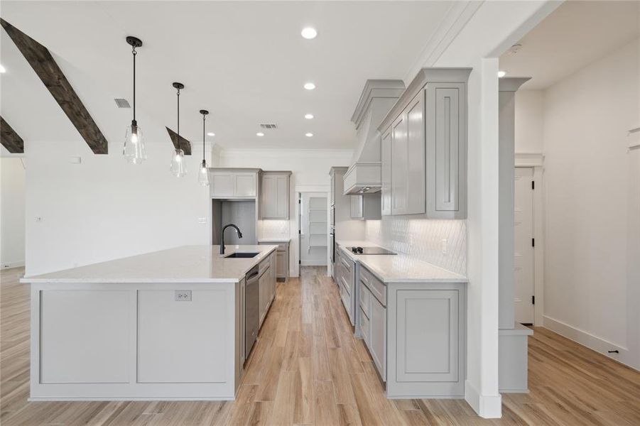 Kitchen with a large island with sink, backsplash, sink, and light hardwood / wood-style flooring