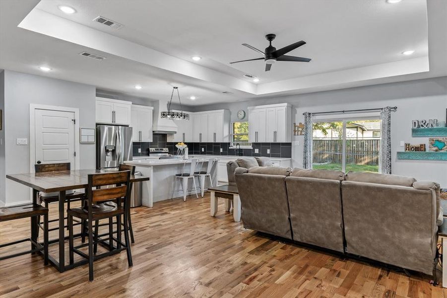 Living room featuring light hardwood / wood-style floors, a tray ceiling, and ceiling fan