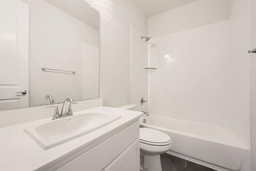 Full bathroom featuring toilet, vanity,  shower combination, and tile patterned flooring