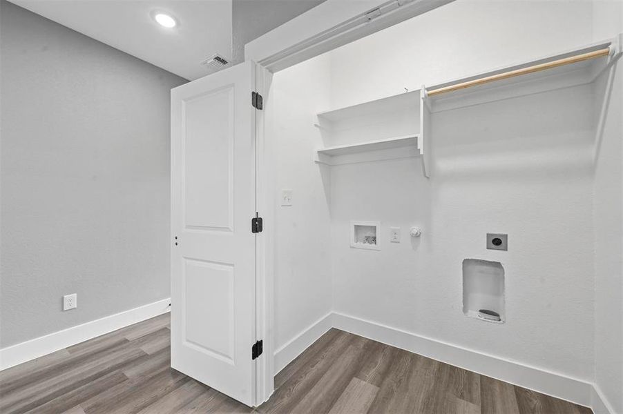 Clothes washing area featuring hookup for a washing machine, hardwood / wood-style flooring, hookup for a gas dryer, and electric dryer hookup