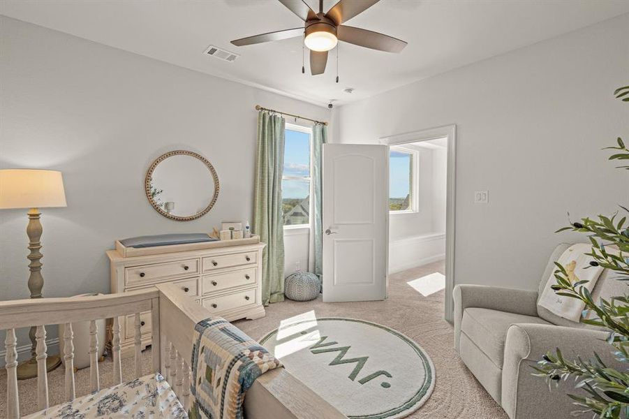 Bedroom featuring ceiling fan, light colored carpet, and a crib