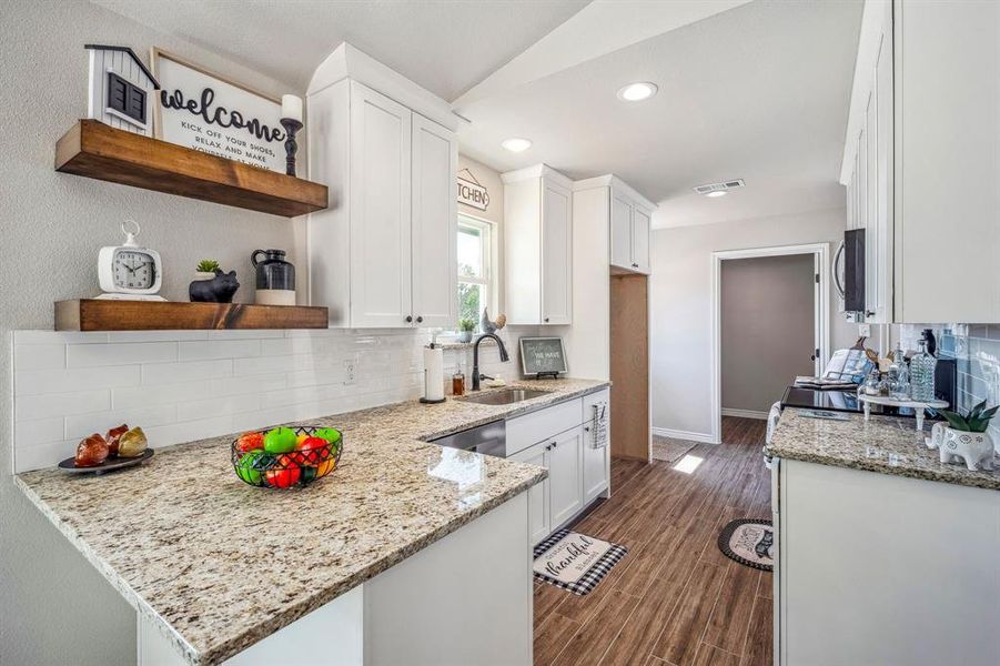 Galley kitchen has granite counters, tile backsplash and floating shelves. Tons of cabinet space and a pantry around the corner!