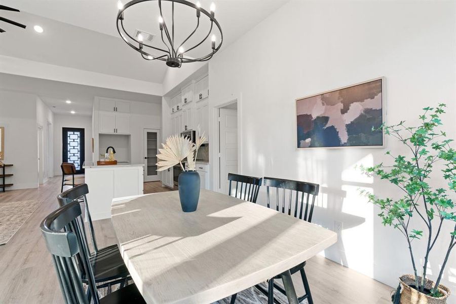 Dining area with ceiling fan with notable chandelier, high vaulted ceiling, sink, and light hardwood / wood-style flooring