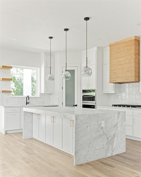Kitchen featuring a center island, tasteful backsplash, light wood-type flooring, and white cabinetry