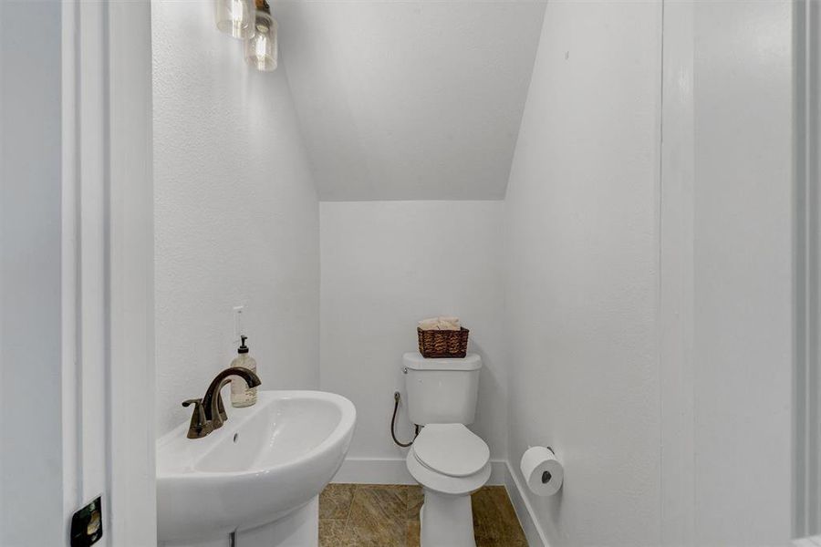 Bathroom featuring sink, lofted ceiling, and toilet