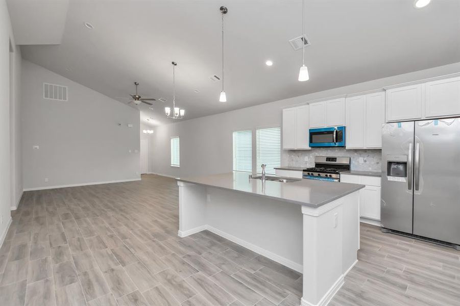 Enjoy the perfect balance of style and efficiency in this modern kitchen. The high-end stainless steel appliances, including a double-door refrigerator, microwave, and gas range, are complemented by durable quartz countertops and sleek cabinetry. **This image is from another Saratoga Home - Wren floorplan.**