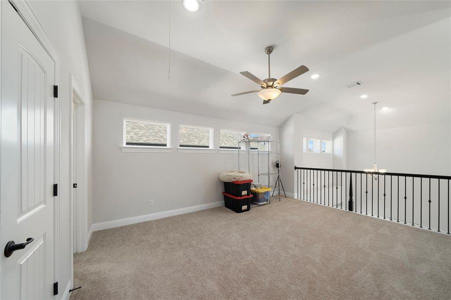 Unfurnished room featuring ceiling fan, light colored carpet, and vaulted ceiling