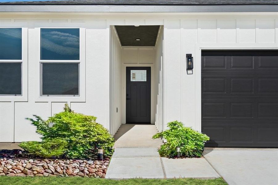 This is a modern single-level home featuring a clean white exterior with contrasting dark garage door, large windows for natural light, and low-maintenance landscaping. Perfect for those seeking a contemporary and streamlined living space.