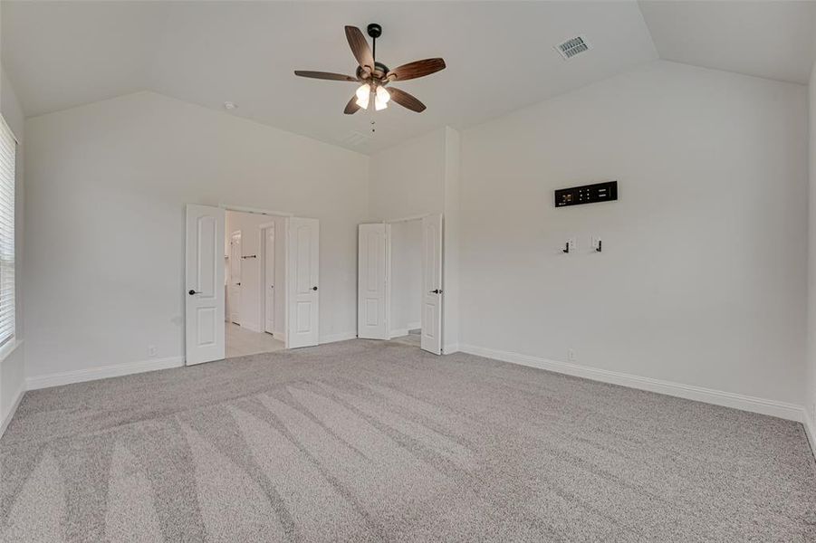 Unfurnished room featuring carpet floors, ceiling fan, and vaulted ceiling