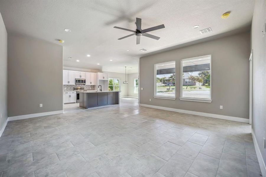 Unfurnished living room with sink, ceiling fan, and plenty of natural light