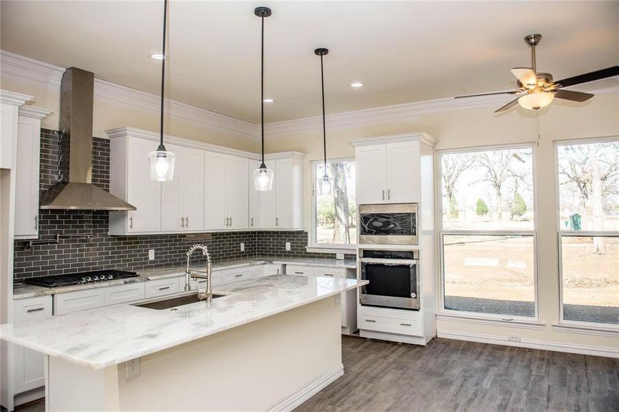 Kitchen featuring tasteful backsplash, sink, wall chimney exhaust hood, white cabinetry, and appliances with stainless steel finishes