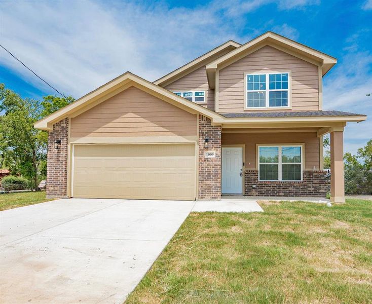 View of front of home with a front yard, a garage, and covered porch