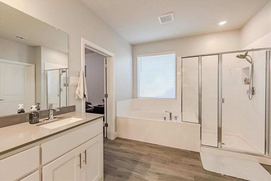 Primary Bathroom featuring shower with separate bathtub, vanity, and hardwood / wood-style floors