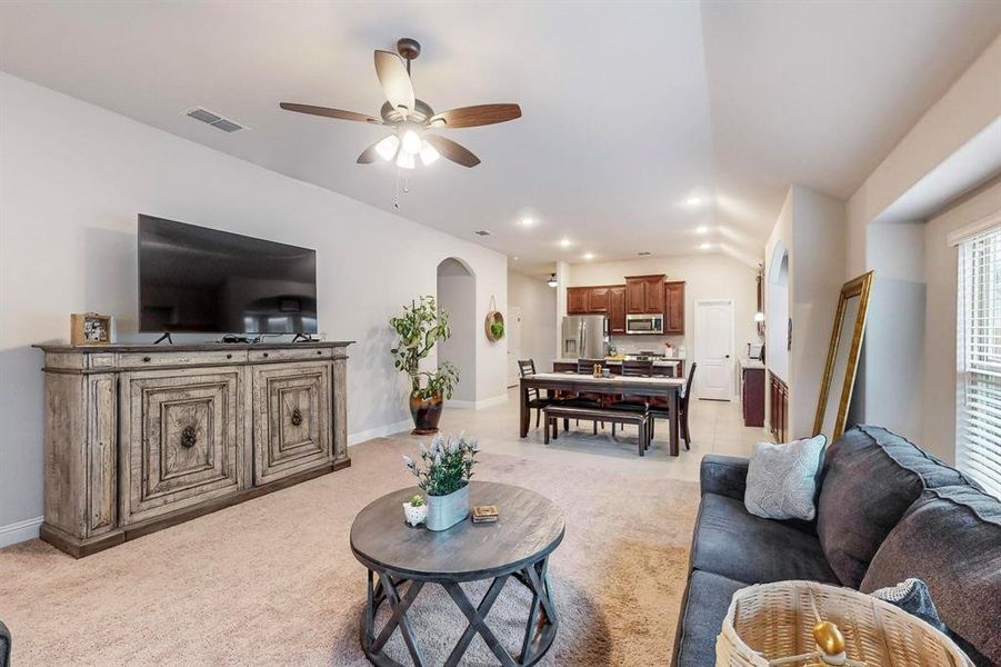 Carpeted living room with lofted ceiling and ceiling fan