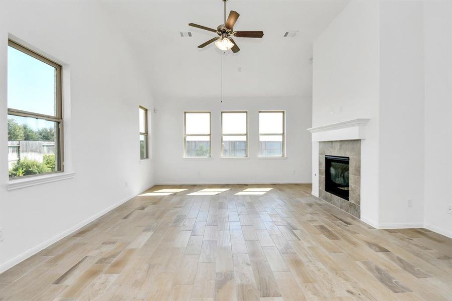 This is a spacious, bright living room with high ceilings, large windows, light floors, and a fireplace.