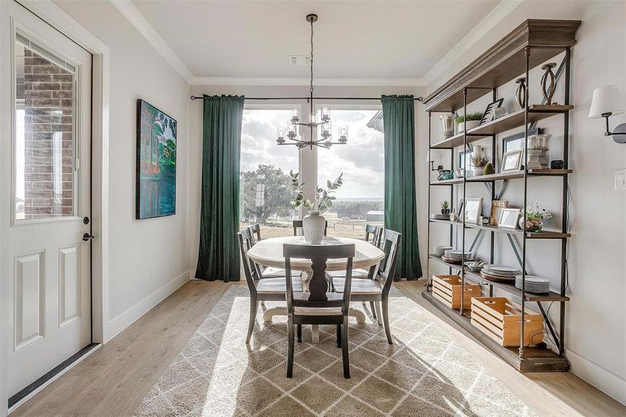 Dining area with an inviting chandelier, light wood-type flooring, and crown molding