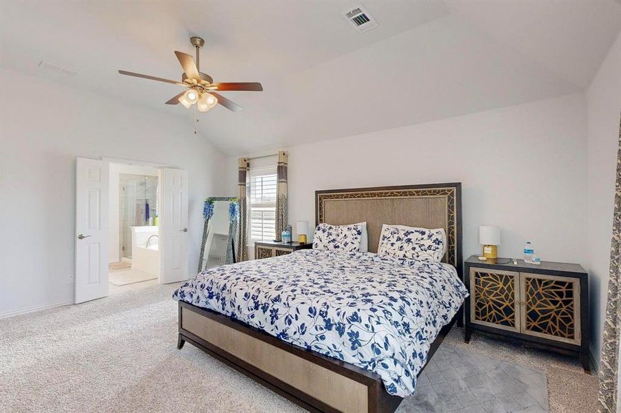 Bedroom featuring ensuite bath, carpet, lofted ceiling, and ceiling fan