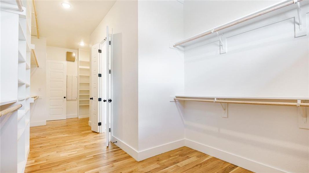 Spacious closet with a barn door and light hardwood / wood-style floors