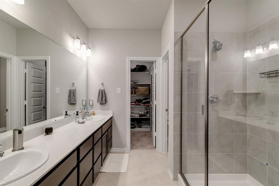 Bathroom with double vanity, tile patterned flooring, and a shower with shower door