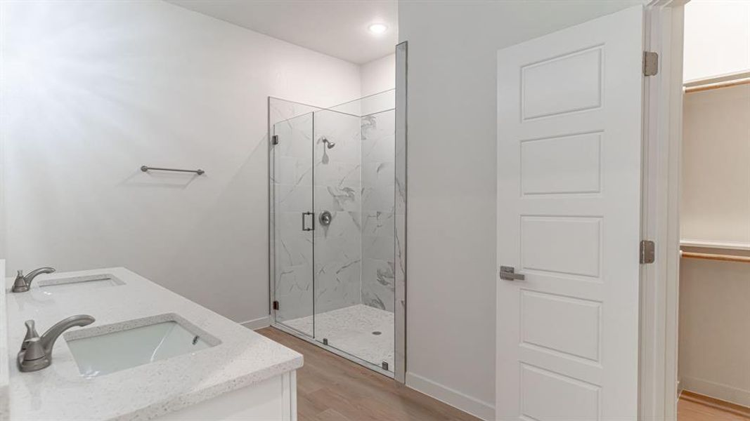 Primary ensuite bath with dual sinks and tiled glass shower