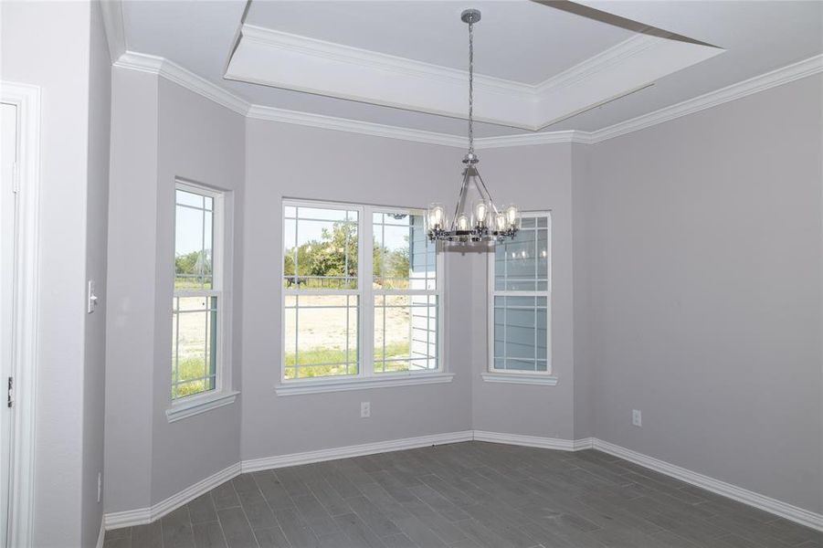 Wonderful dining room with lots of natural light, modern light fixture, tray ceiling and wood-look tile floor.