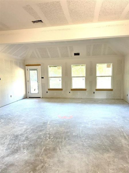 Spare room with lofted ceiling and concrete flooring