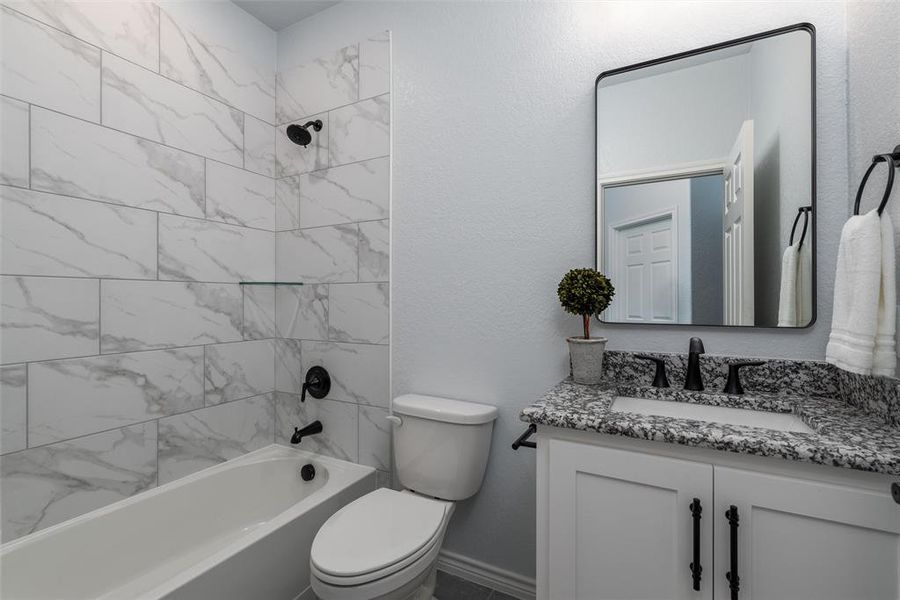 The full-sized second bathroom with granite, custom tile-work, and combined shower/bathtub.